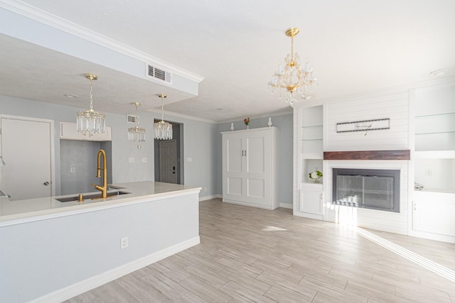 kitchen featuring sink, built in features, light hardwood / wood-style flooring, decorative light fixtures, and ornamental molding