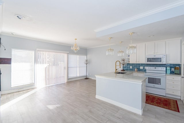 kitchen with white appliances, backsplash, sink, hanging light fixtures, and white cabinetry