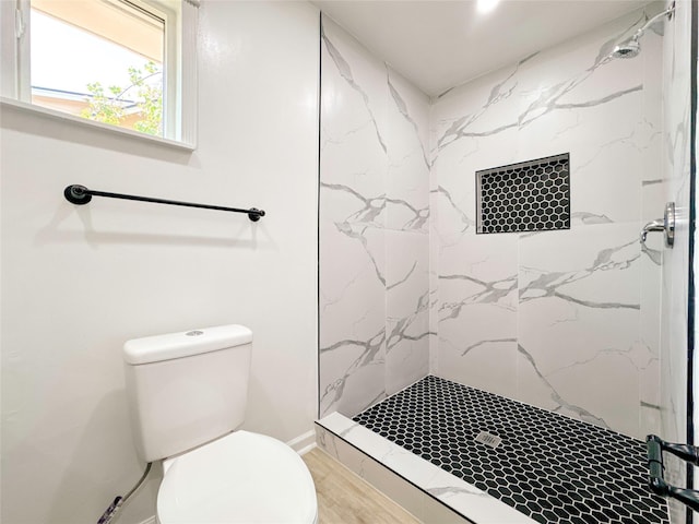 bathroom featuring tiled shower, hardwood / wood-style floors, and toilet