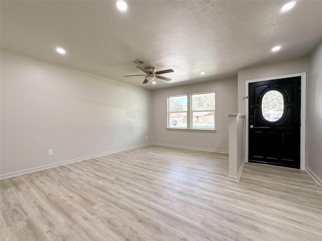 foyer entrance with ceiling fan, light hardwood / wood-style flooring, and a textured ceiling