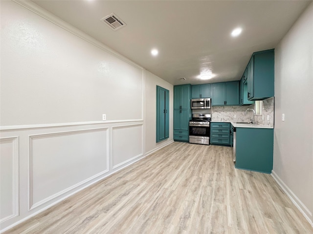 kitchen featuring sink, light wood-type flooring, ornamental molding, tasteful backsplash, and stainless steel appliances