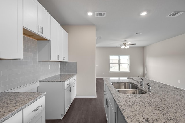 kitchen featuring backsplash, light stone counters, ceiling fan, sink, and white cabinets