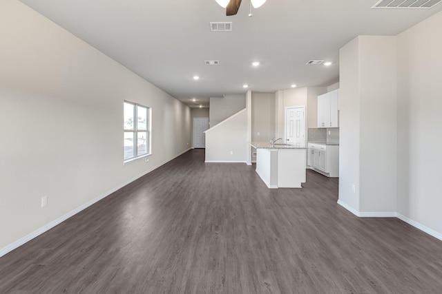 unfurnished living room featuring dark hardwood / wood-style flooring, ceiling fan, and sink