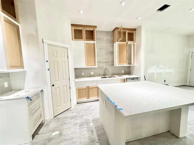 kitchen featuring dishwasher, light brown cabinets, sink, backsplash, and a kitchen island