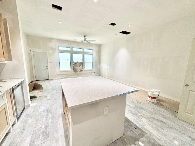 kitchen with ceiling fan, dishwasher, light hardwood / wood-style flooring, light brown cabinetry, and a kitchen island