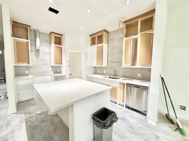 kitchen featuring decorative backsplash, light brown cabinetry, stainless steel dishwasher, sink, and a center island