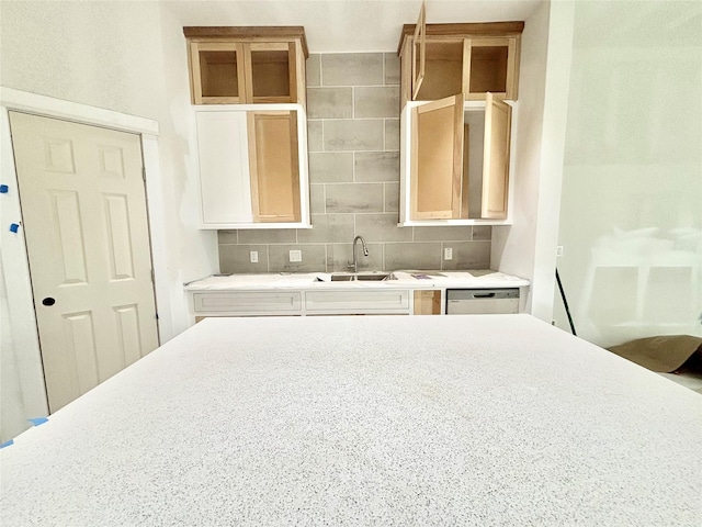 kitchen with stainless steel dishwasher, decorative backsplash, and sink