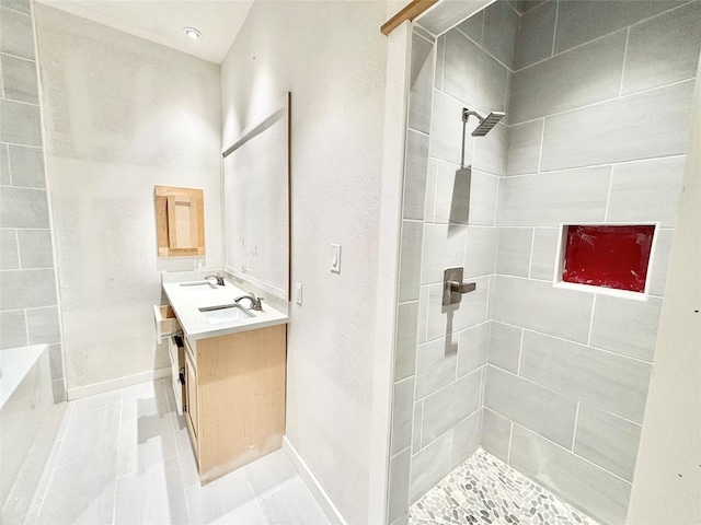 bathroom featuring tiled shower, vanity, and tile patterned flooring