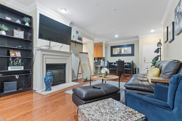 living room featuring built in shelves, crown molding, and light hardwood / wood-style flooring