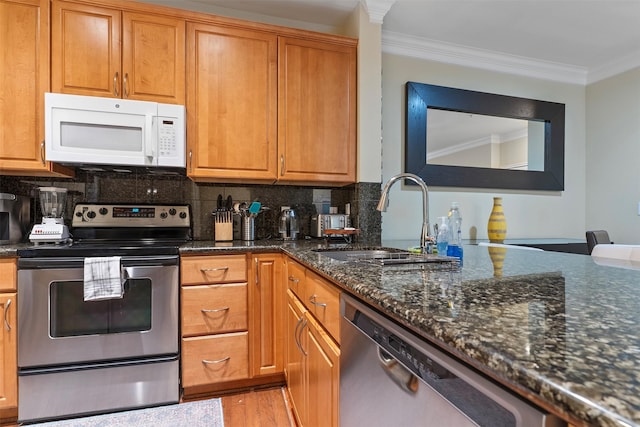 kitchen featuring sink, ornamental molding, tasteful backsplash, dark stone counters, and appliances with stainless steel finishes