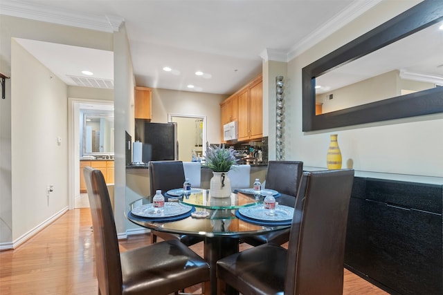 dining space with light wood-type flooring and crown molding