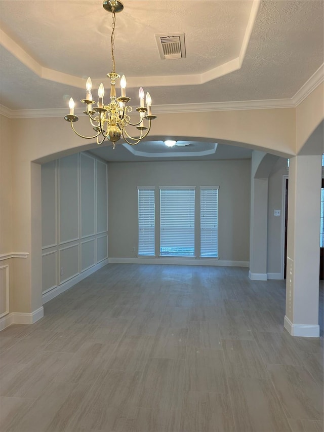 unfurnished room with a raised ceiling, crown molding, a chandelier, and a textured ceiling