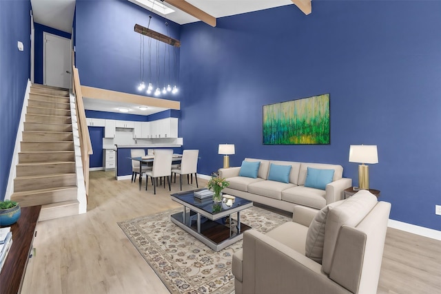 living room featuring beamed ceiling, a towering ceiling, and light hardwood / wood-style flooring