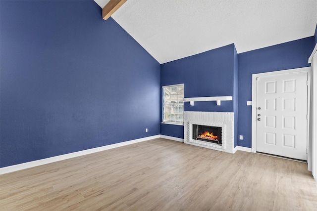 unfurnished living room featuring vaulted ceiling with beams, hardwood / wood-style flooring, and a brick fireplace