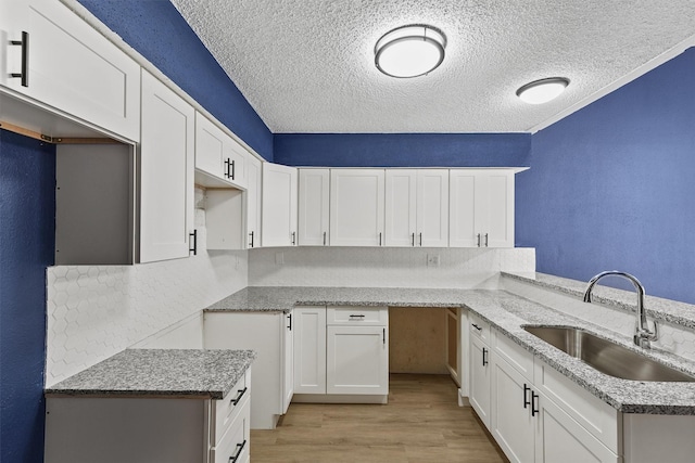 kitchen featuring white cabinets, light stone countertops, sink, and a textured ceiling