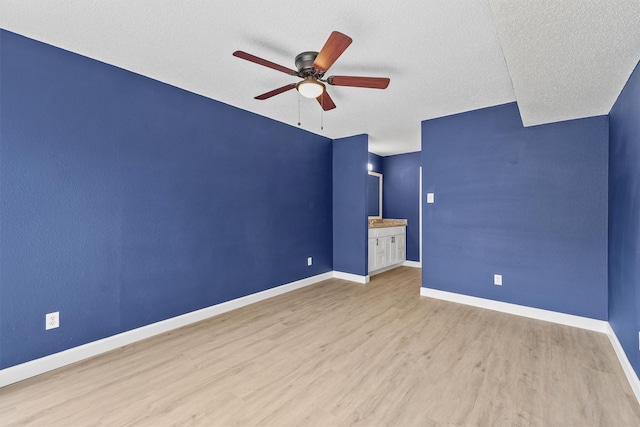 unfurnished bedroom featuring a textured ceiling, ensuite bath, light hardwood / wood-style flooring, and ceiling fan