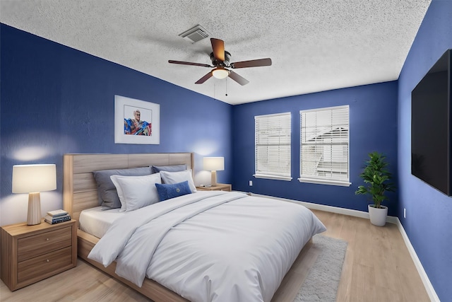 bedroom with a textured ceiling, light hardwood / wood-style floors, and ceiling fan