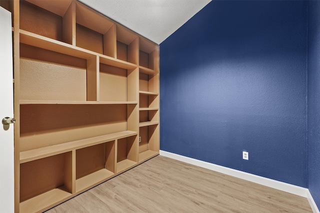 spare room with built in shelves, hardwood / wood-style flooring, and lofted ceiling