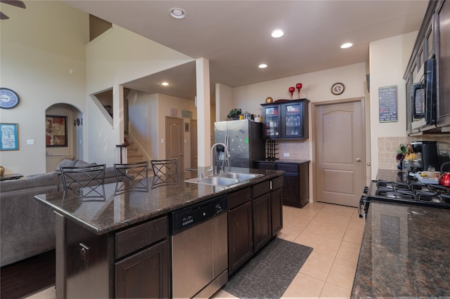 kitchen with a kitchen island with sink, sink, decorative backsplash, light tile patterned floors, and stainless steel appliances