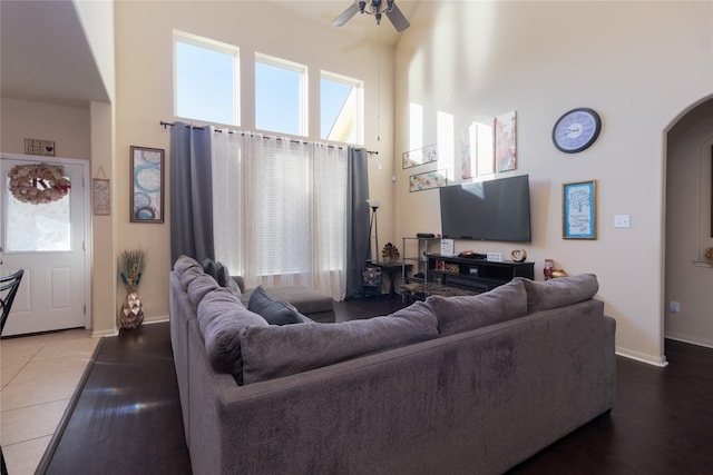 living room featuring ceiling fan, wood-type flooring, and a towering ceiling