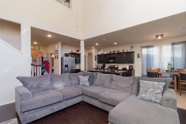 living room featuring dark hardwood / wood-style flooring and a towering ceiling