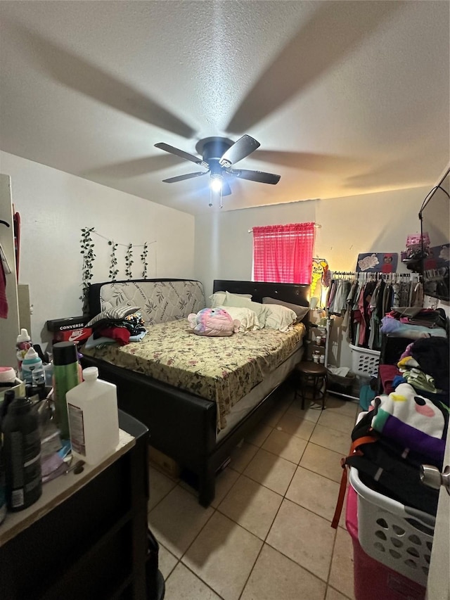 bedroom featuring ceiling fan, light tile patterned floors, and a textured ceiling