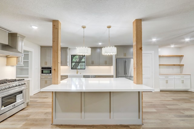 kitchen with gray cabinetry, a large island, stainless steel appliances, and light hardwood / wood-style flooring