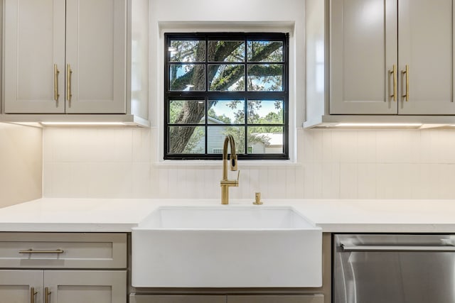 interior details with tasteful backsplash, gray cabinets, sink, and stainless steel dishwasher