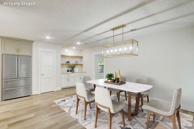 dining room with light hardwood / wood-style floors and a textured ceiling