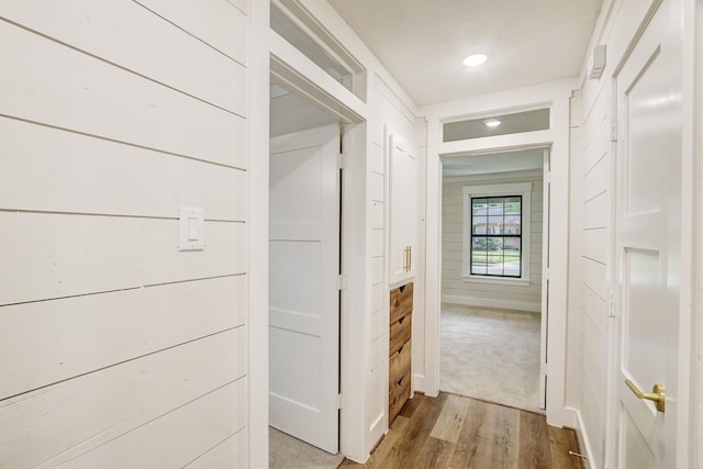 hallway with wood walls and light hardwood / wood-style flooring