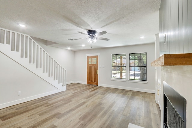 foyer entrance with a textured ceiling, light hardwood / wood-style flooring, and ceiling fan