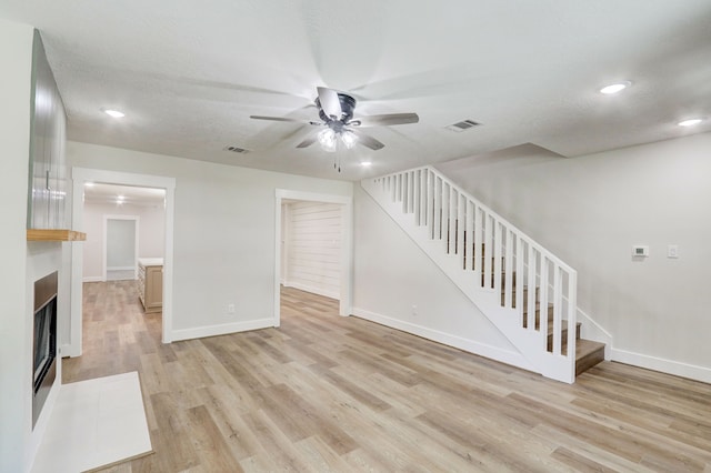 unfurnished living room featuring ceiling fan, light hardwood / wood-style floors, and a textured ceiling