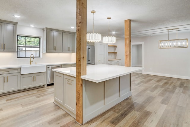 kitchen with stainless steel dishwasher, a textured ceiling, sink, decorative light fixtures, and light hardwood / wood-style floors