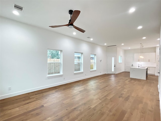 unfurnished living room featuring hardwood / wood-style floors, ceiling fan, and sink