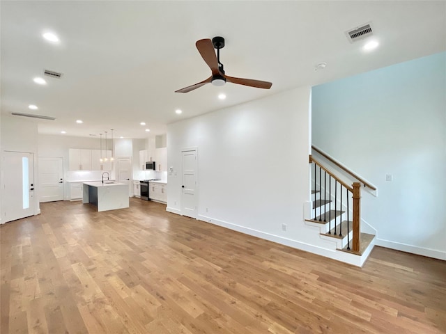 unfurnished living room with light hardwood / wood-style floors, ceiling fan, and sink