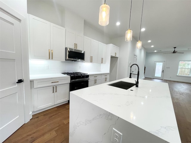 kitchen featuring pendant lighting, a center island with sink, white cabinetry, and sink