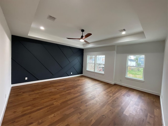 unfurnished room with hardwood / wood-style floors, a tray ceiling, and ceiling fan