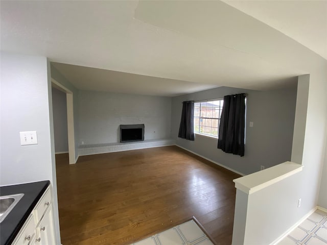 unfurnished living room featuring a large fireplace, wood-type flooring, and sink