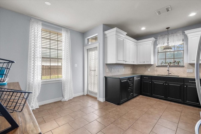 kitchen with dark cabinets, white cabinetry, a sink, and decorative light fixtures