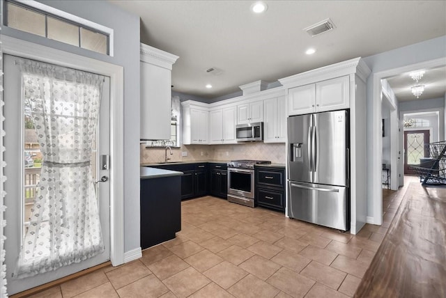 kitchen with visible vents, decorative backsplash, appliances with stainless steel finishes, white cabinets, and a sink