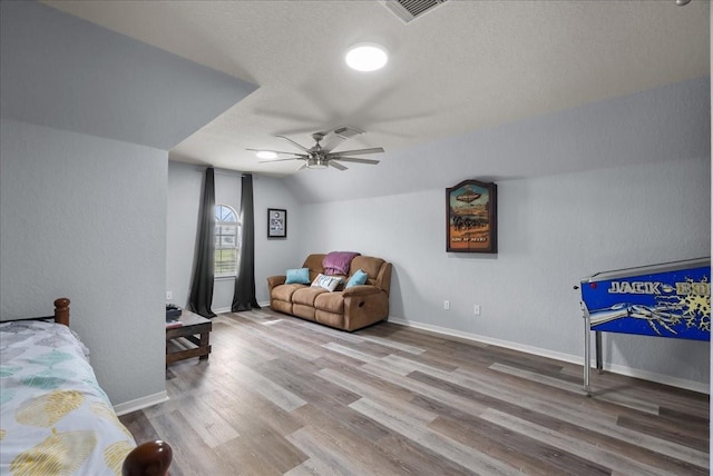 bedroom with baseboards, visible vents, lofted ceiling, wood finished floors, and a textured ceiling