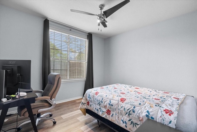 bedroom with a ceiling fan, light wood-type flooring, a textured ceiling, and baseboards