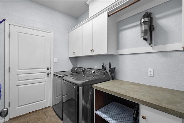 washroom with a textured wall, cabinet space, and independent washer and dryer