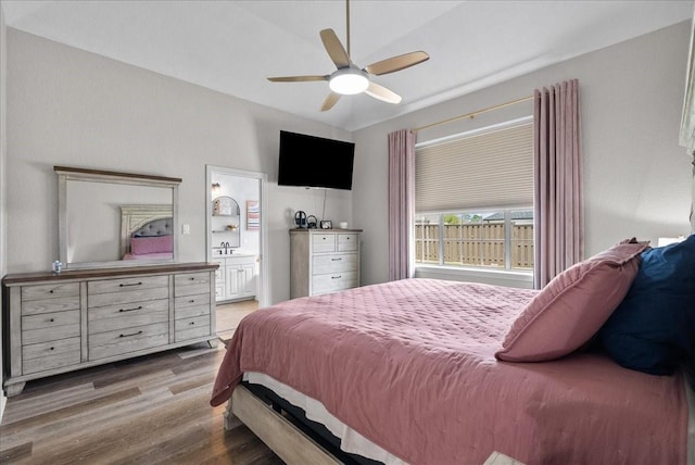 bedroom with light wood finished floors, ceiling fan, connected bathroom, and a sink