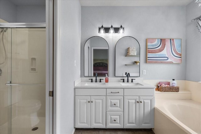 bathroom featuring a stall shower, a sink, a bath, and double vanity