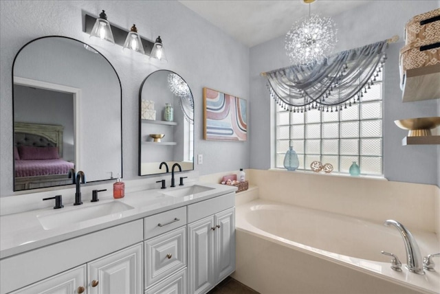 bathroom with double vanity, a garden tub, a sink, and ensuite bathroom