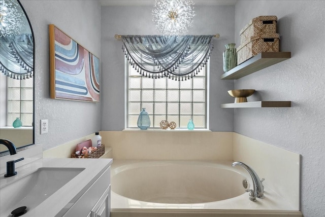 bathroom featuring a garden tub, vanity, and a textured wall