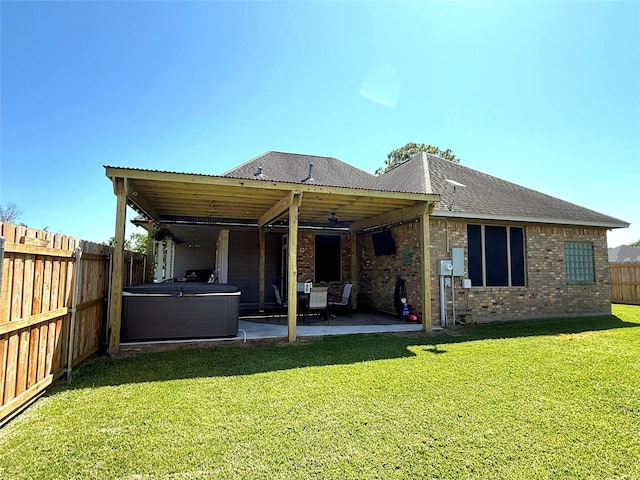 rear view of property with a patio area, a yard, a fenced backyard, and a hot tub