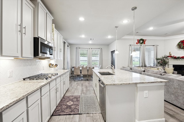 kitchen featuring pendant lighting, sink, an island with sink, appliances with stainless steel finishes, and white cabinetry