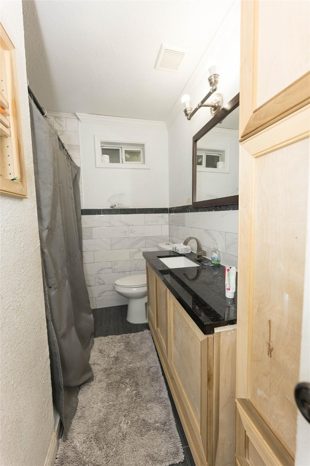 bathroom featuring vanity, a shower with curtain, crown molding, toilet, and tile walls